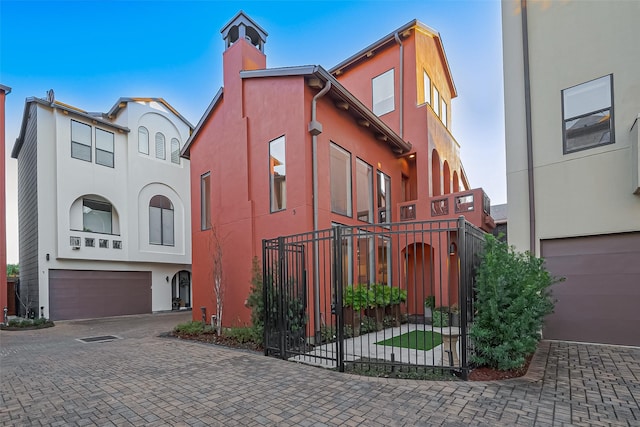 view of home's exterior with stucco siding, an attached garage, a chimney, and decorative driveway