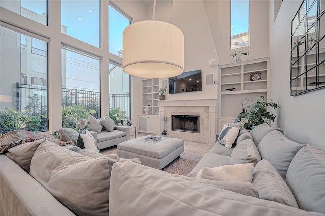 living area featuring built in features, a high ceiling, and a tiled fireplace