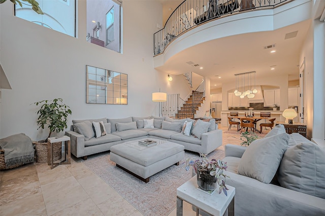 living room with visible vents, a high ceiling, and stairs