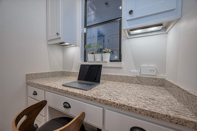 interior space featuring light stone countertops and white cabinets