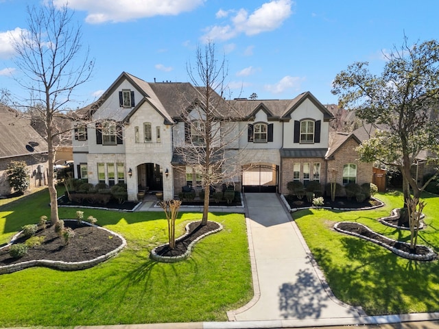 french provincial home featuring stucco siding, stone siding, a front lawn, and driveway