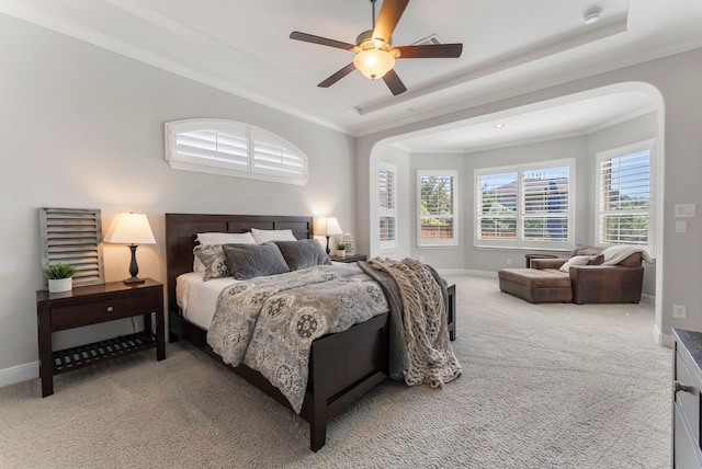 carpeted bedroom with baseboards, a raised ceiling, and crown molding