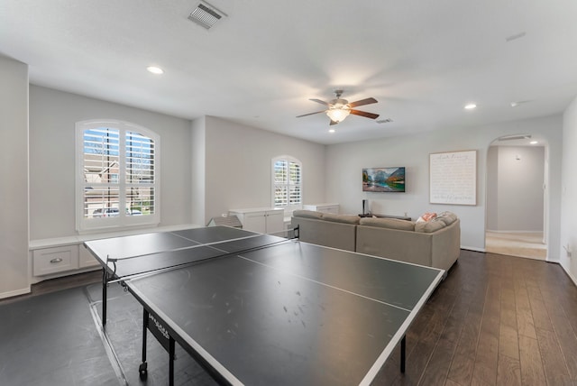 recreation room with dark wood finished floors, arched walkways, visible vents, and a healthy amount of sunlight