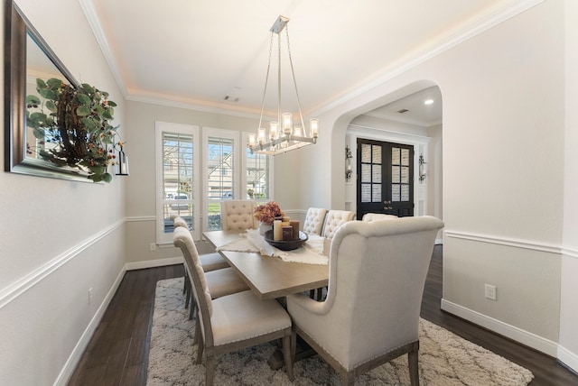 dining space featuring visible vents, baseboards, ornamental molding, arched walkways, and dark wood-style flooring