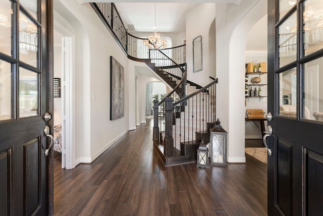 foyer with a notable chandelier, plenty of natural light, arched walkways, and dark wood-type flooring