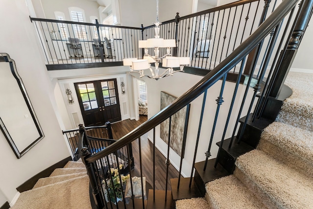 stairs with a notable chandelier, a healthy amount of sunlight, a high ceiling, and baseboards