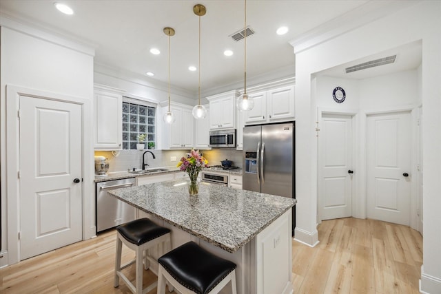727 Dorothy St, Houston, TX 77007 - kitchen with stainless steel appliances, a sink, light wood-style flooring, white cabinets, and ornamental molding
