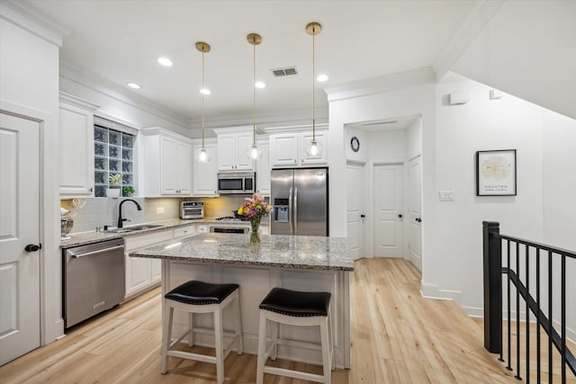 727 Dorothy St, Houston, TX 77007 - kitchen featuring appliances with stainless steel finishes, a sink, white cabinets, light wood finished floors, and a kitchen island