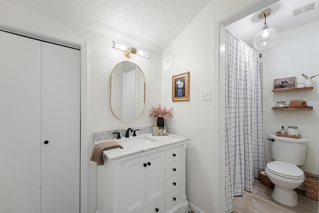 full bath with vanity, wood finished floors, visible vents, a textured ceiling, and toilet