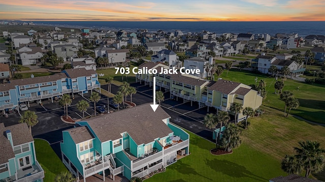 aerial view at dusk featuring a residential view and a water view