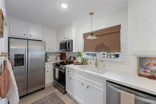 kitchen featuring a sink, decorative backsplash, light countertops, stainless steel appliances, and white cabinetry