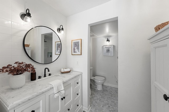 bathroom featuring toilet, vanity, and baseboards