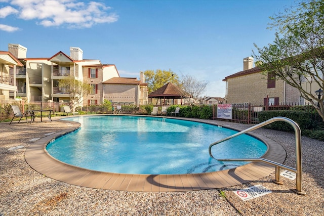 community pool featuring a gazebo, fence, and a residential view