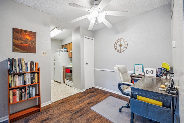 office space with a ceiling fan, a textured ceiling, wood finished floors, baseboards, and a textured wall