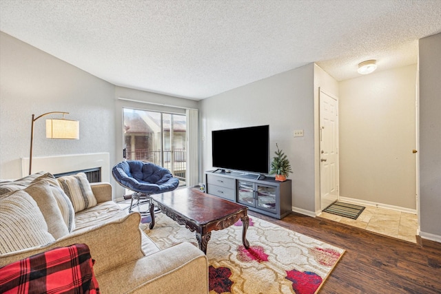 living area with a textured ceiling, baseboards, and wood finished floors