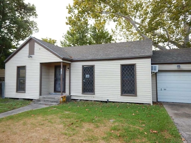 ranch-style house with an attached garage, driveway, a front yard, and roof with shingles