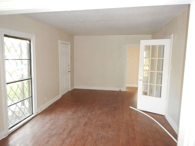 unfurnished room featuring plenty of natural light, baseboards, and wood finished floors