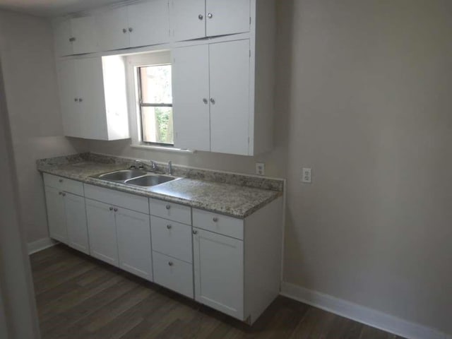 kitchen featuring dark wood-style flooring, white cabinetry, baseboards, and a sink