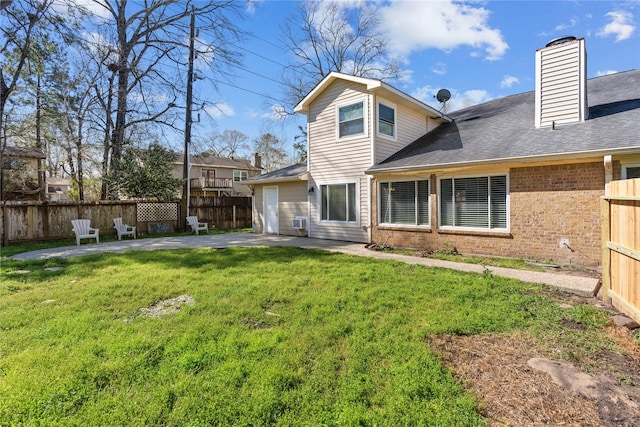 back of house featuring brick siding, a lawn, a patio, and fence