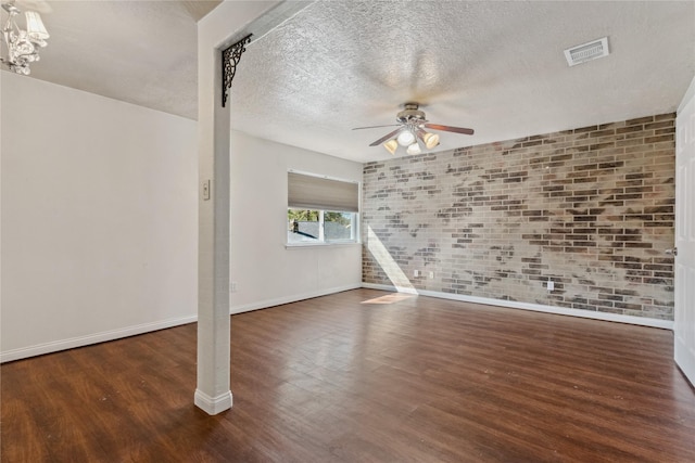 empty room with visible vents, a textured ceiling, wood finished floors, and ceiling fan with notable chandelier