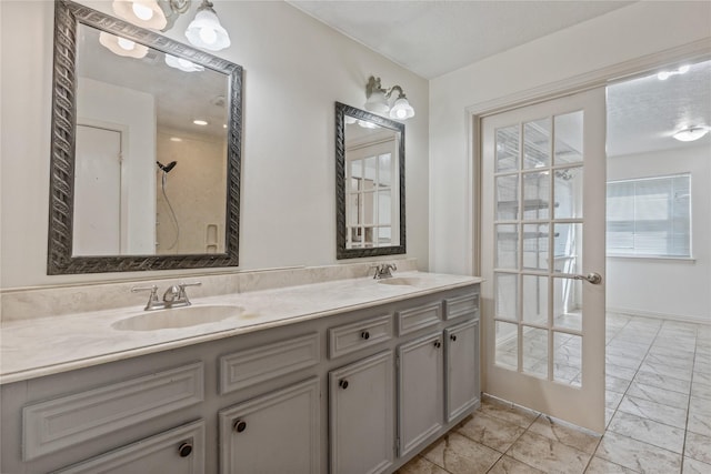 bathroom featuring double vanity, french doors, baseboards, and a sink