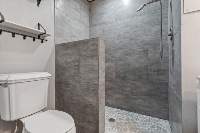 full bathroom featuring a tile shower and toilet