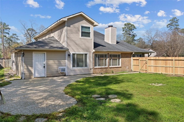 rear view of property featuring brick siding, a chimney, a lawn, and fence