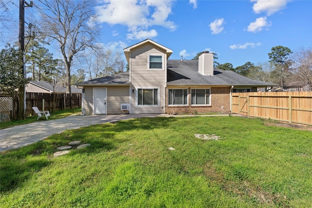 back of property featuring a yard, brick siding, fence private yard, and a chimney