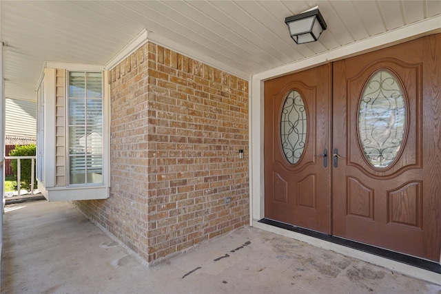 entrance to property featuring brick siding and covered porch