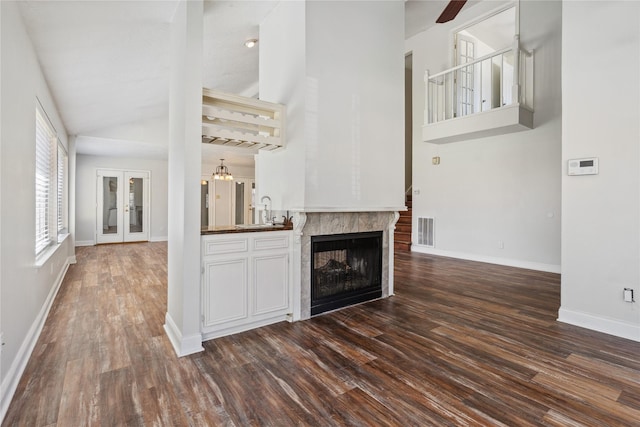 bar with baseboards, visible vents, dark wood-style flooring, a tile fireplace, and a sink