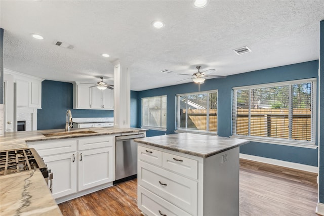 kitchen with dishwasher, light wood-type flooring, visible vents, and a sink