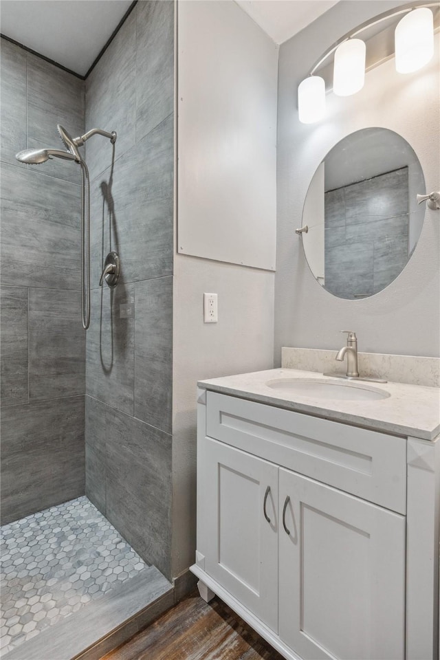 full bathroom with vanity, wood finished floors, and a tile shower