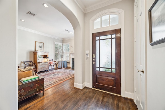 foyer entrance featuring arched walkways, visible vents, crown molding, and hardwood / wood-style flooring