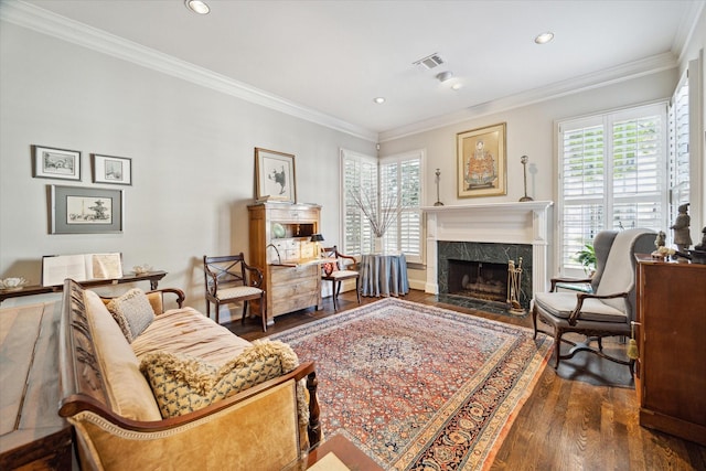 living area featuring wood finished floors, visible vents, a premium fireplace, recessed lighting, and ornamental molding