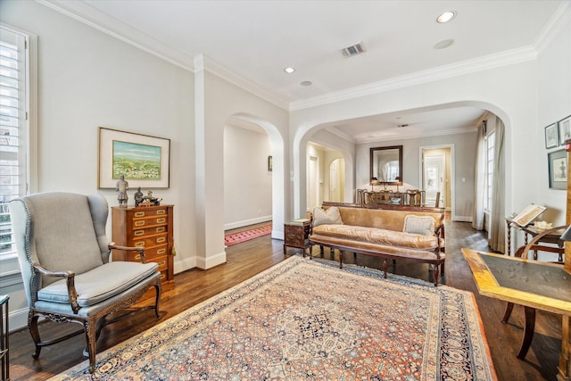 living room featuring visible vents, ornamental molding, wood finished floors, arched walkways, and baseboards