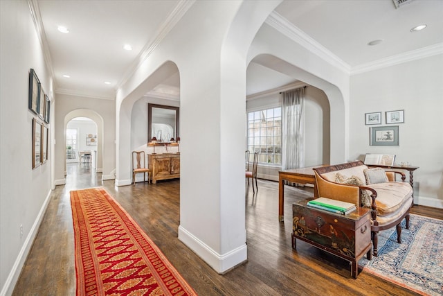 hallway featuring arched walkways, ornamental molding, baseboards, and wood finished floors