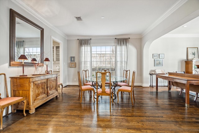 dining area featuring arched walkways, dark wood-type flooring, baseboards, and ornamental molding