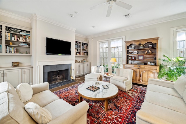 living room featuring a fireplace, crown molding, a ceiling fan, and wood finished floors