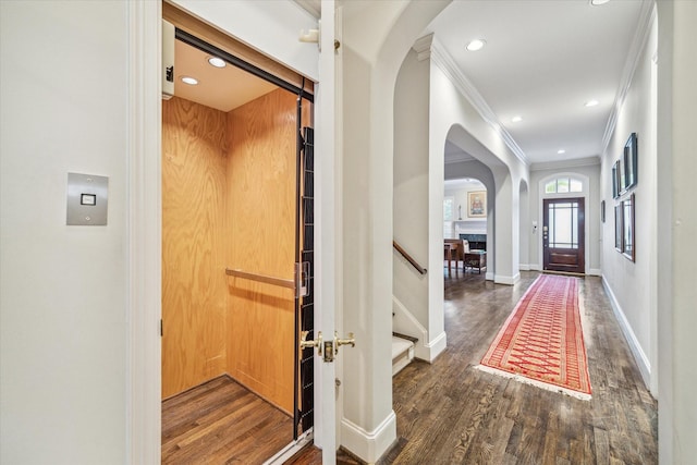 entrance foyer with crown molding, elevator, wood finished floors, and baseboards