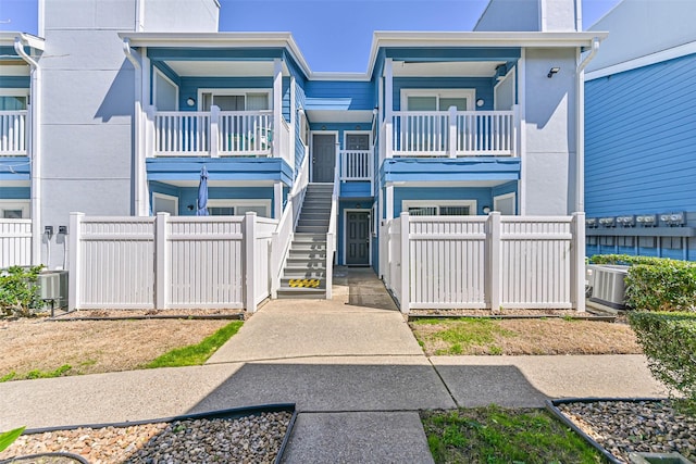 view of front of property featuring a fenced front yard, central AC, and stairway