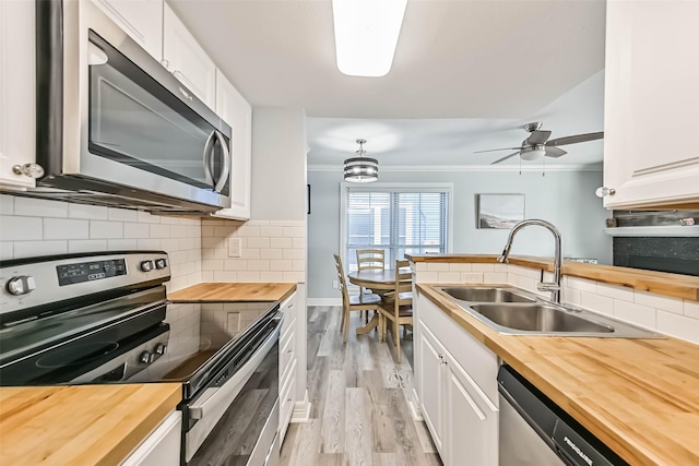 kitchen featuring a sink, ornamental molding, appliances with stainless steel finishes, and butcher block countertops