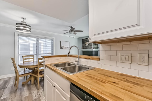 kitchen with a sink, backsplash, butcher block counters, and crown molding