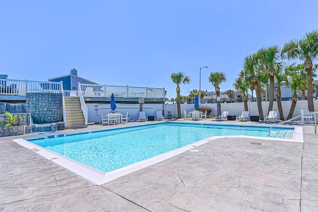 pool featuring a patio, stairway, and fence