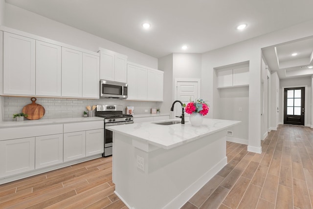 kitchen featuring a sink, stainless steel appliances, wood finish floors, and backsplash