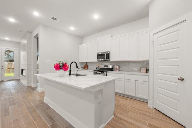 kitchen with tasteful backsplash, visible vents, wood tiled floor, appliances with stainless steel finishes, and a sink