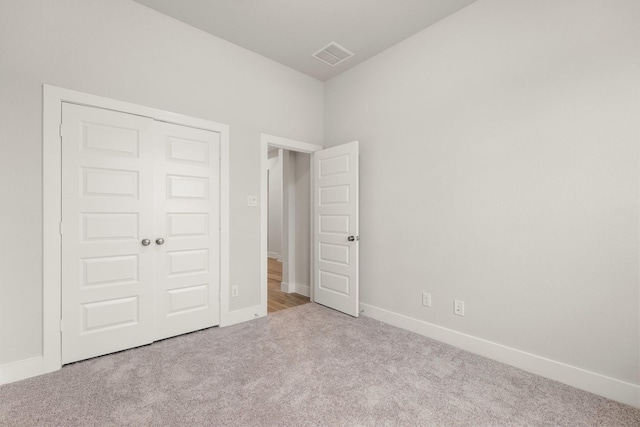 unfurnished bedroom with a closet, visible vents, carpet flooring, and baseboards