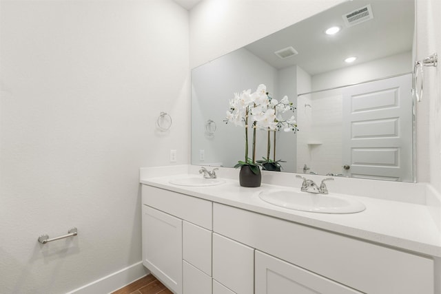 full bathroom featuring double vanity, visible vents, wood finished floors, and a sink