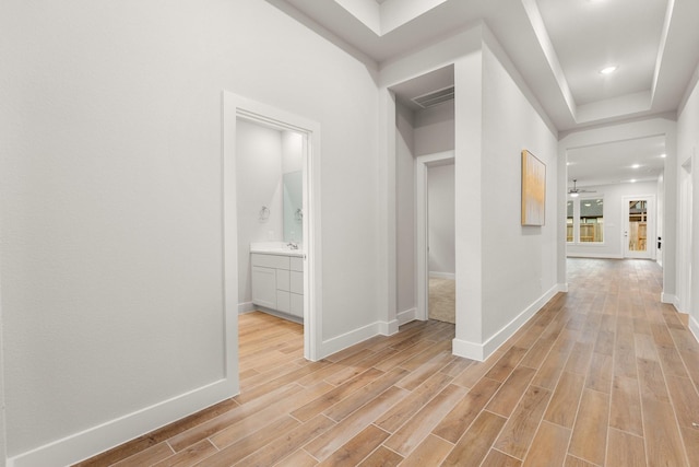 corridor with light wood-type flooring and baseboards