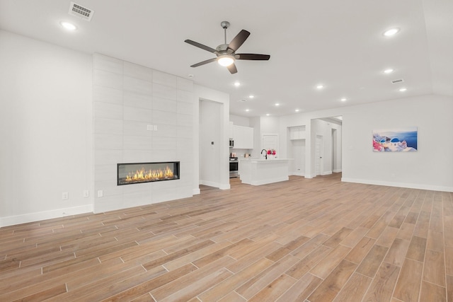 unfurnished living room with visible vents, recessed lighting, a fireplace, and light wood-style floors