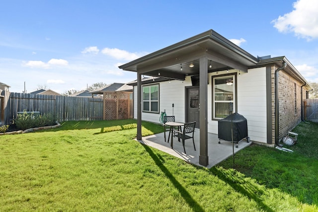 back of house featuring a yard, a patio area, brick siding, and a fenced backyard